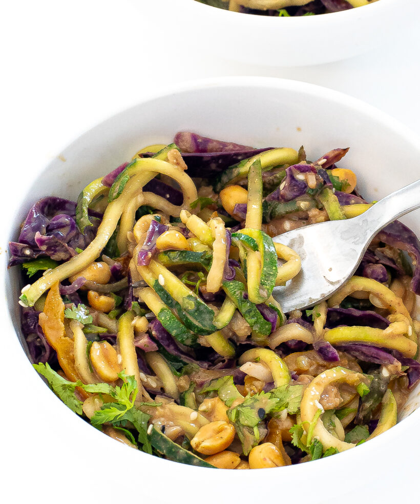 Thai peanut zucchini noodles in a white bowl with a fork. 
