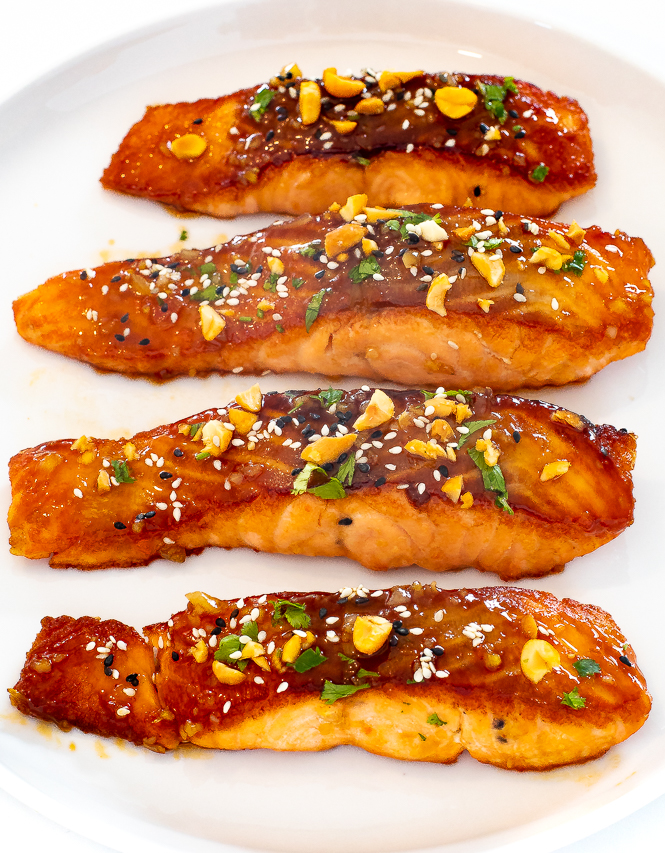 salmon brushed with sauce on white plate with peanuts and cilantro