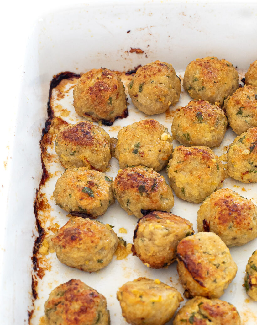 Chicken meatballs lined up in a baking dish after being baked. 