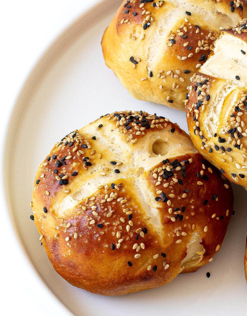 homemade pretzel buns topped with sesame seeds on plate