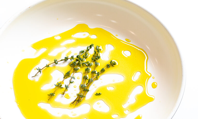 Olive oil and thyme sprigs in a skillet.