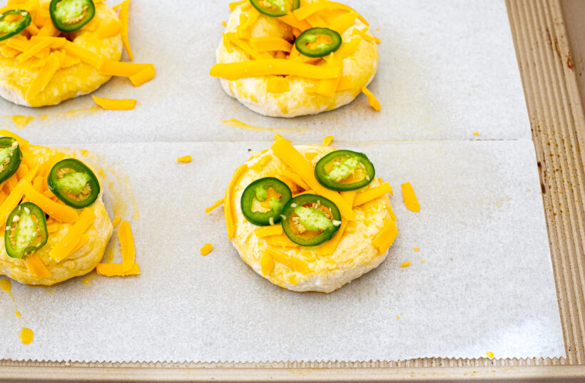 Bagels topped with shredded cheese and jalapeno slices.