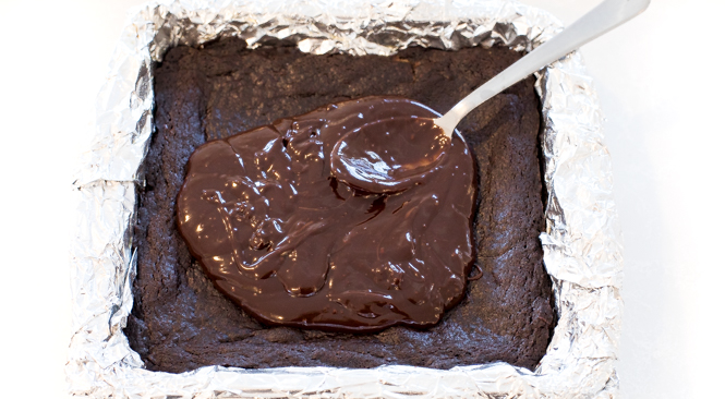 Topping cooled chocolate brownies with homemade chocolate ganache