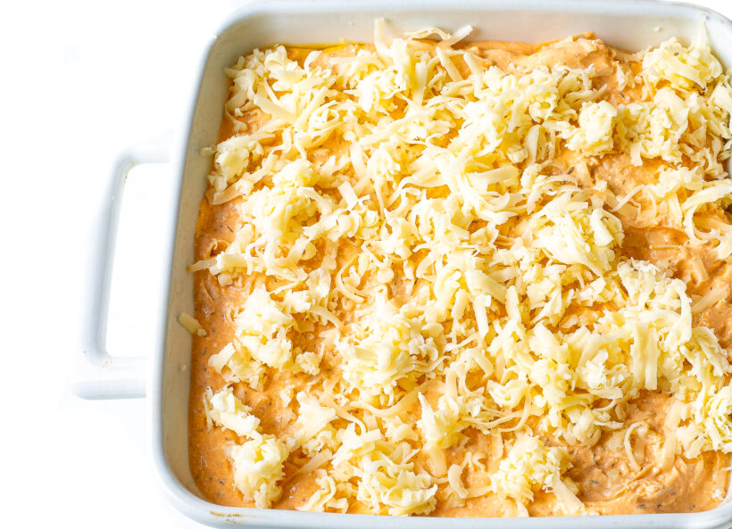 Buffalo chicken dip with shredded cheese added on top.