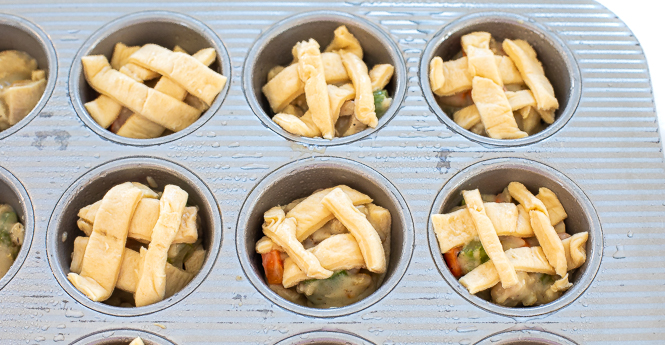 Mini chicken pot pies assembled in a muffin tin and ready to be baked. 