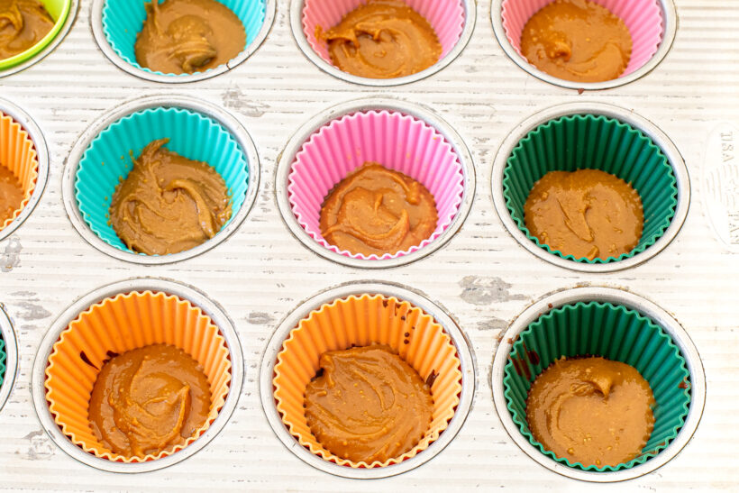 Peanut butter layered on top of a chocolate layer in a silicone muffin tin.