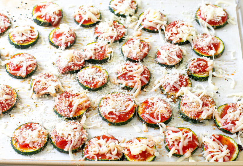 Zucchini pizza bites with cheese on top before being baked.
