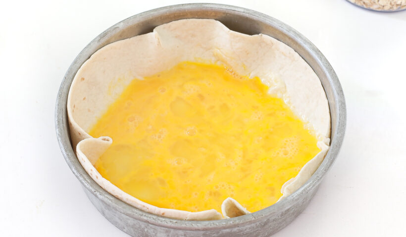 Eggs in a tortilla that is set inside a cake pan.