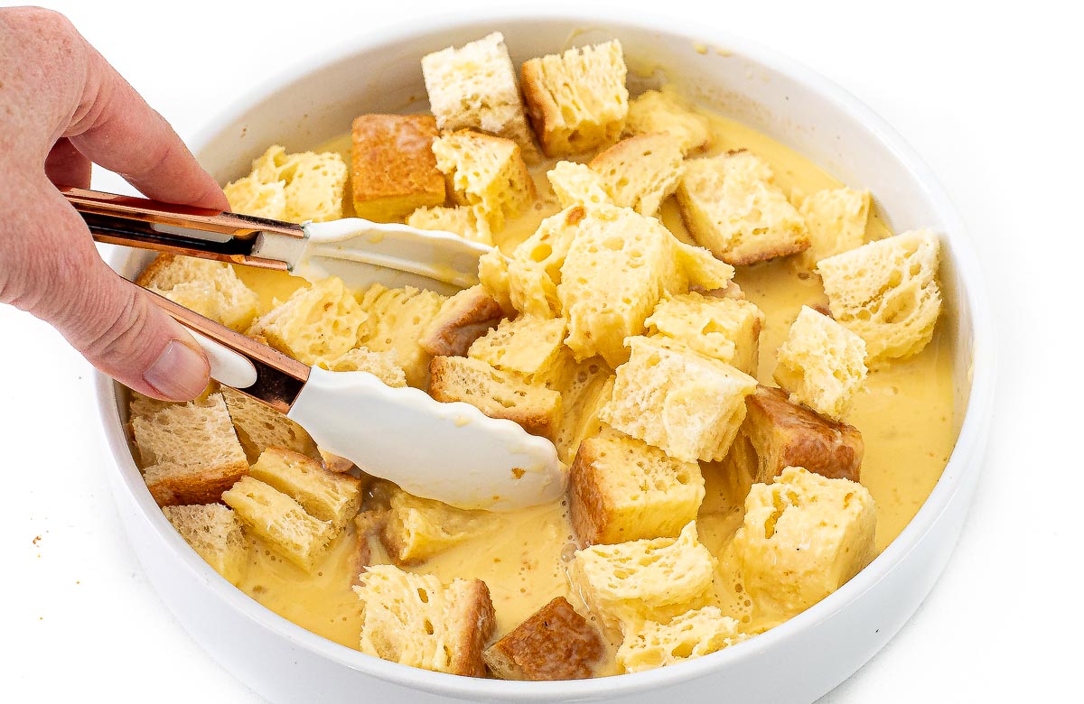 tossing cubed brioche bread into egg custard