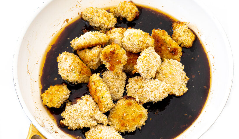 tossing crispy breaded chicken bites in asian sauce