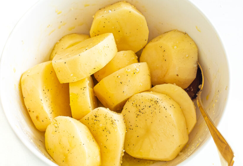 Potato medallions in a bowl with olive oil, salt and pepper. 