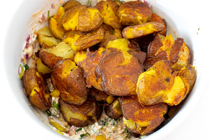 Smashed potatoes in a white mixing bowl.