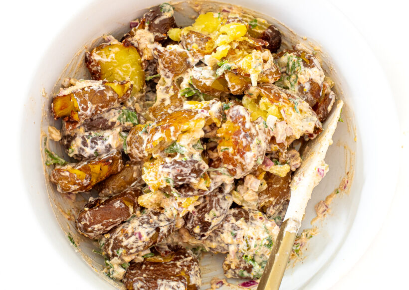 Roasted potato salad in a white mixing bowl.