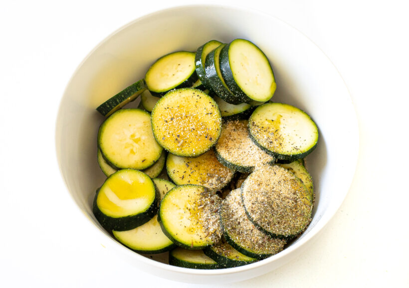 Zucchini slices in a bowl with spices.