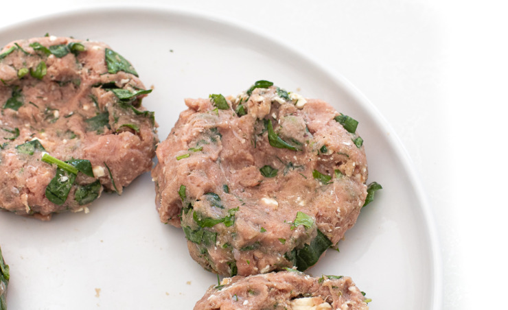 Raw turkey burgers on a white plate. 