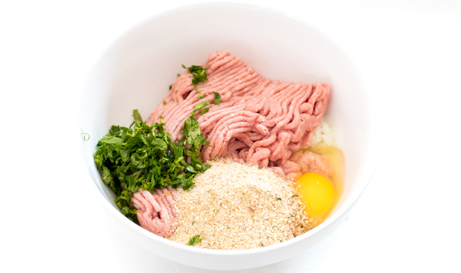 ingredients for meatballs in a white bowl