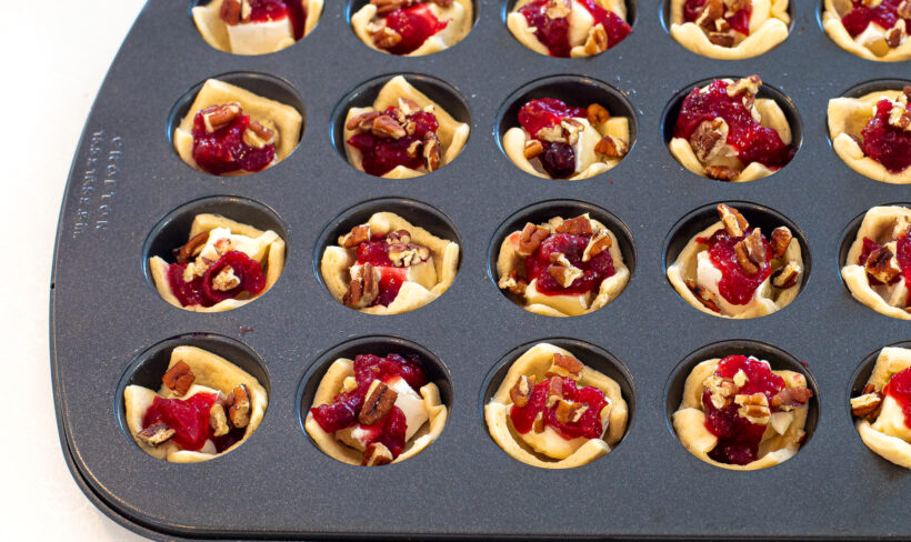Brie cranberry bites assembled in a muffin tin before being baked. 