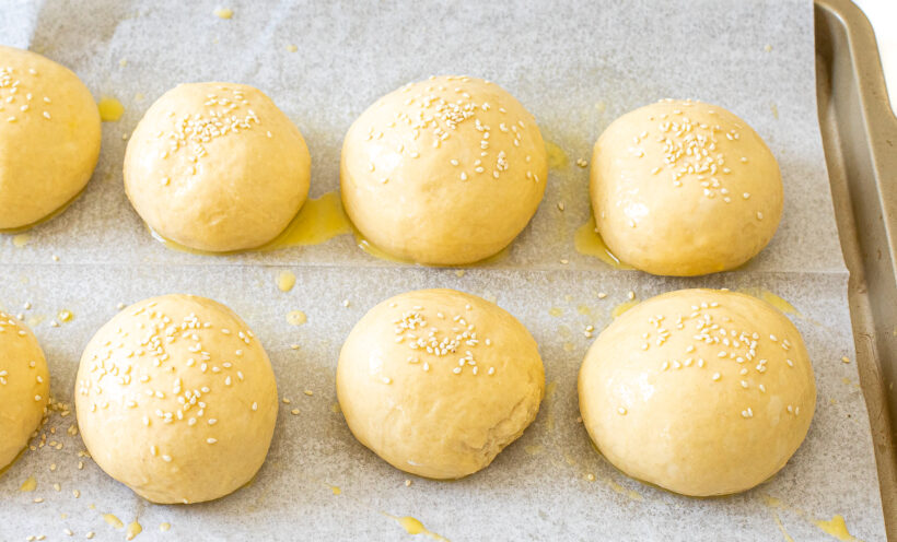 unbaked burger buns on baking sheet
