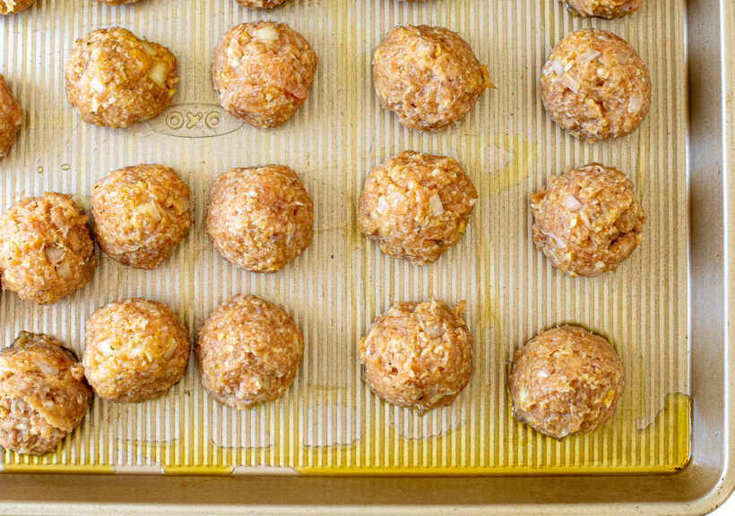 Uncooked meatballs placed on a baking sheet.
