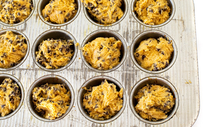 Muffin batter divided into a muffin tin.