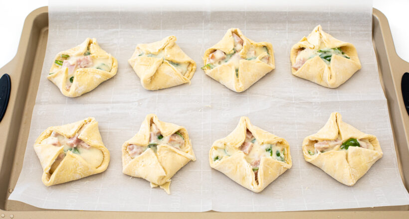 Ham and cheese puff pastry on a baking sheet before being baked. 