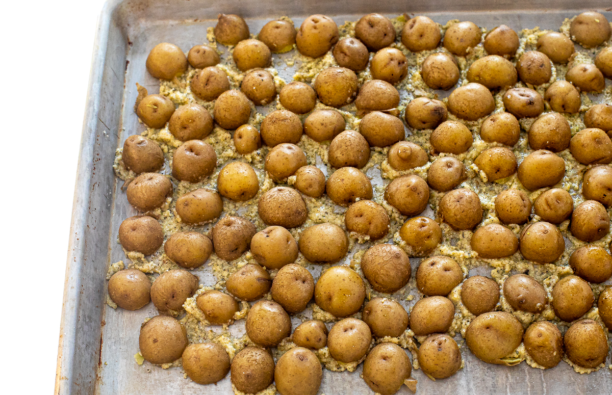 Potatoes on a sheet pan, cut side down sitting in the parmesan butter. 
