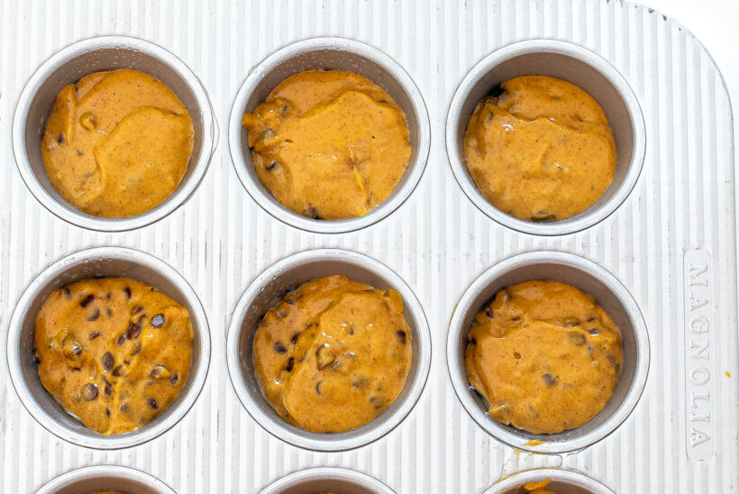 Muffin batter in a greased muffin tin before being baked.