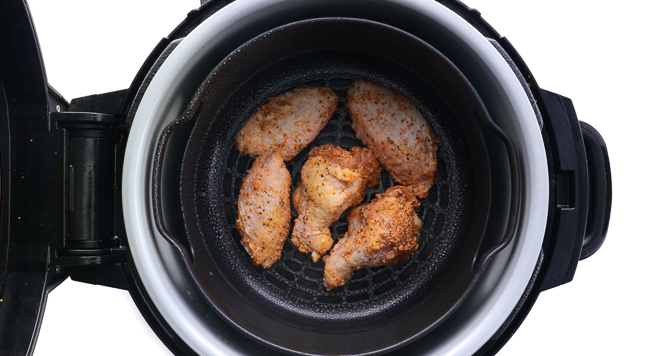 placing uncooked seasoned chicken wings in the air fryer