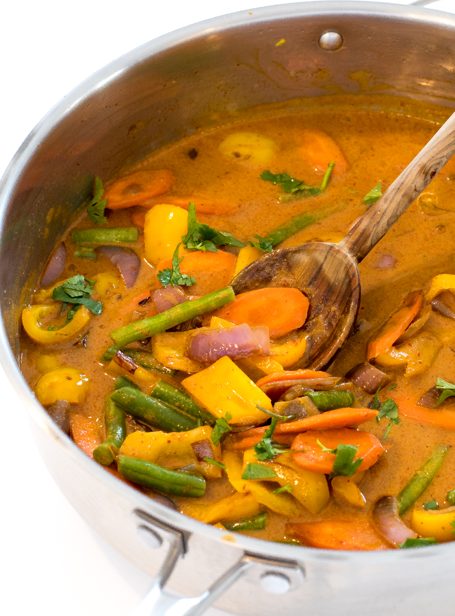 curry vegetables in skillet with a wooden spoon