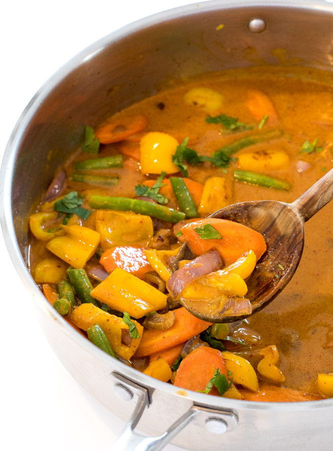 Thai vegetable curry in a pot with a wooden spoon.