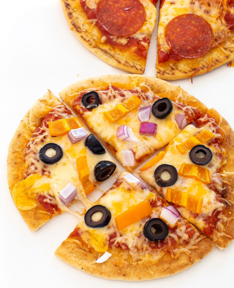pita pizza topped with olives, red onion and bell peppers