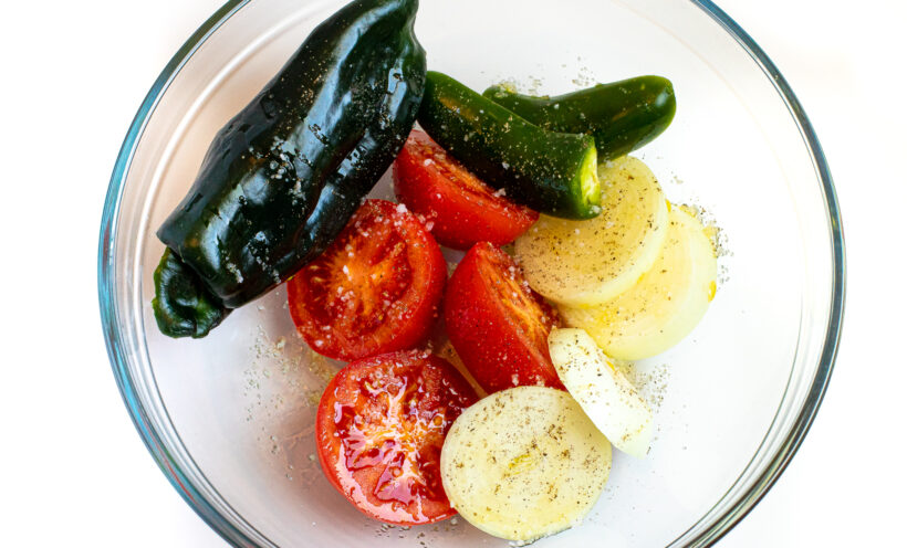 Veggies for roasted tomato chili salsa in a glass mixing bowl.