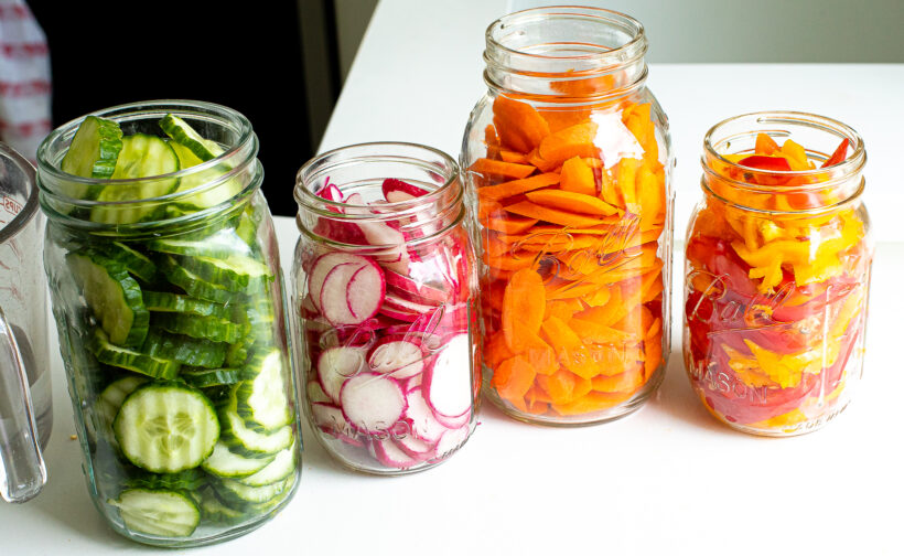 Mason jars filled with sliced vegetables.