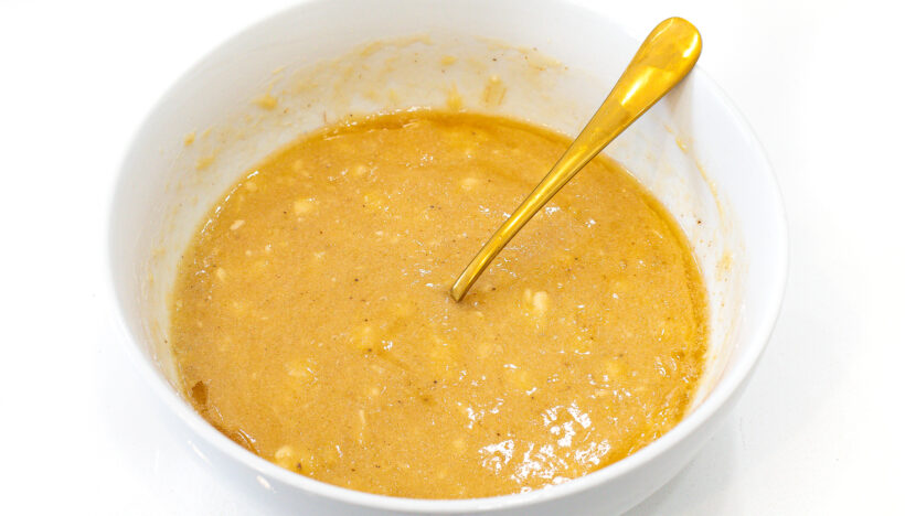 Banana mixed with wet ingredients in a white bowl.