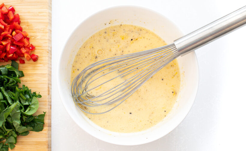 Eggs being whisked together in a white mixing bowl.