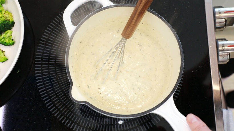 overhead shot of author whisking cheese sauce on stove