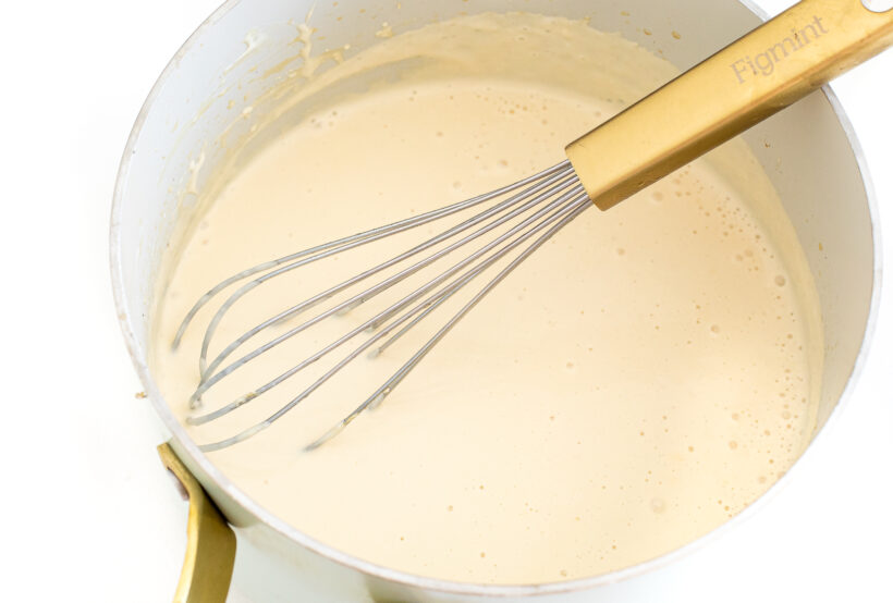 Cream cheese and chicken broth being whisked in a saucepan.