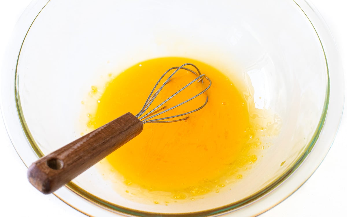 whisking egg yolks in clear glass bowl