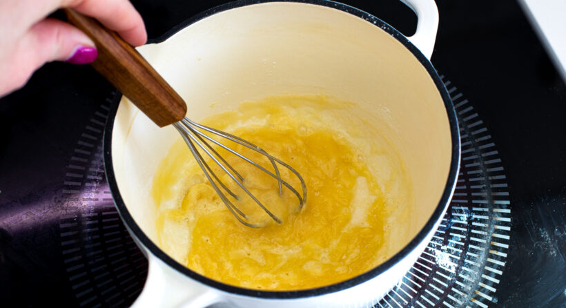 Butter and flour being whisked together in a saucepan. 