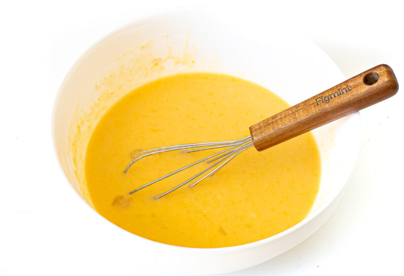 Wet ingredients needed for muffins being whisked in a large bowl.