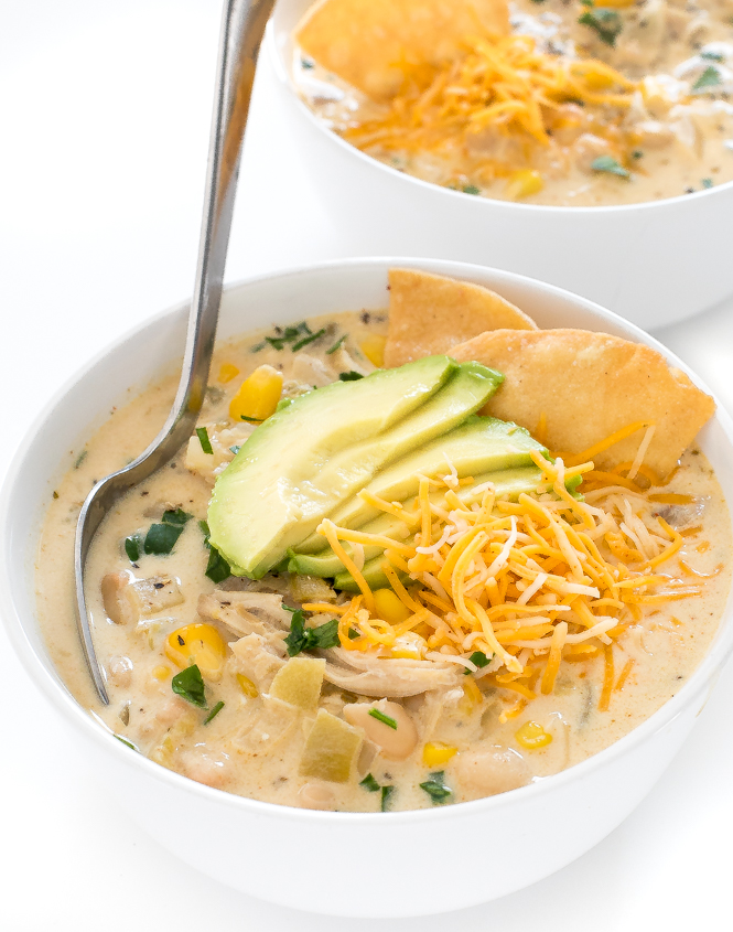 bowl of White Chicken Chili with shredded cheese and avocado on top