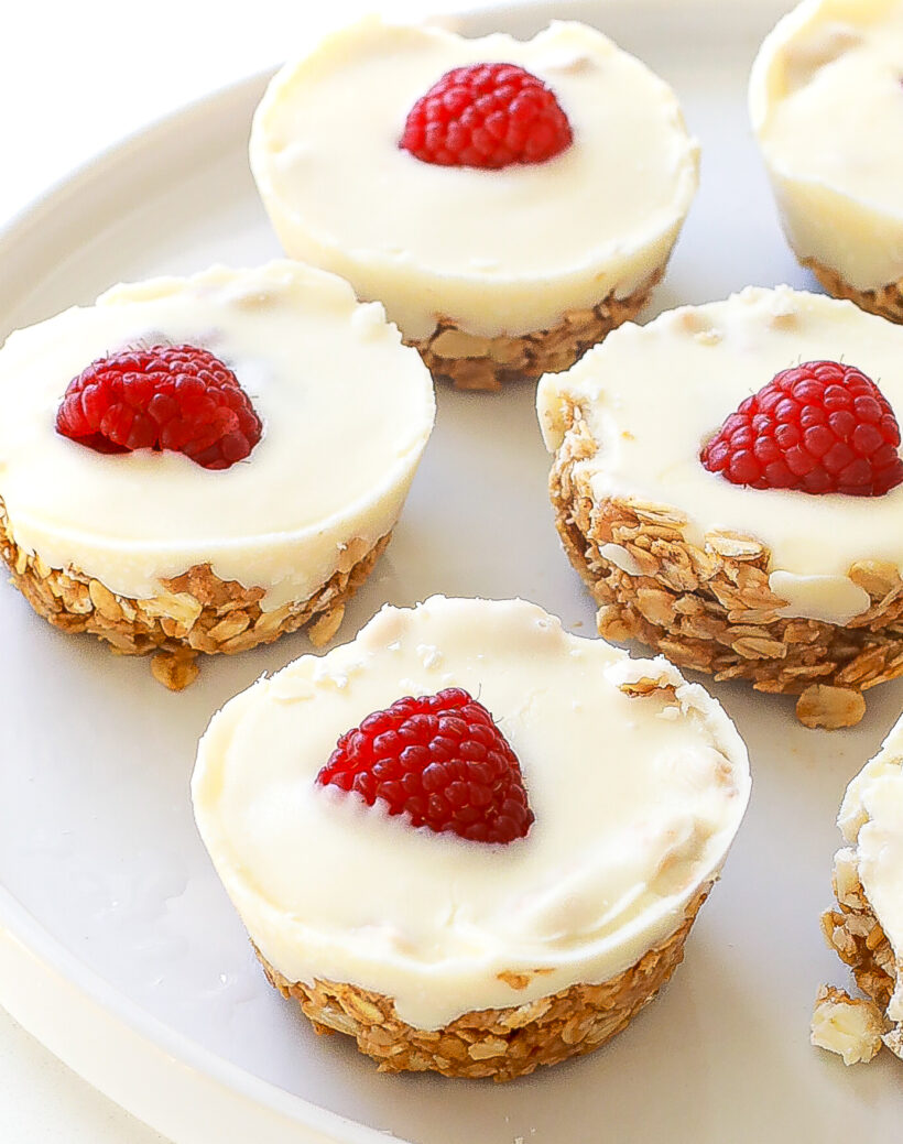 Close up of oat cups with oat mixture topped with white chocolate and a raspberry.