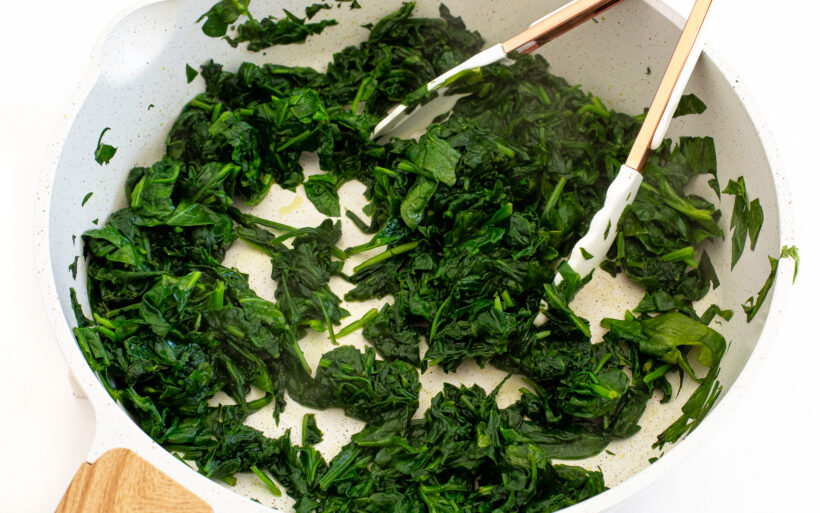 Spinach being cooked in a skillet. 