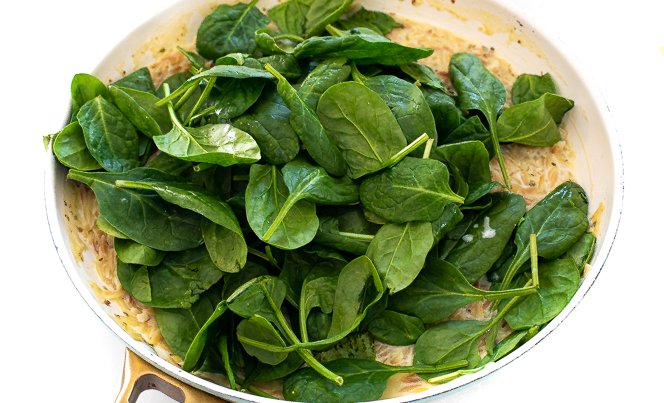 Spinach in a skillet to be cooked.