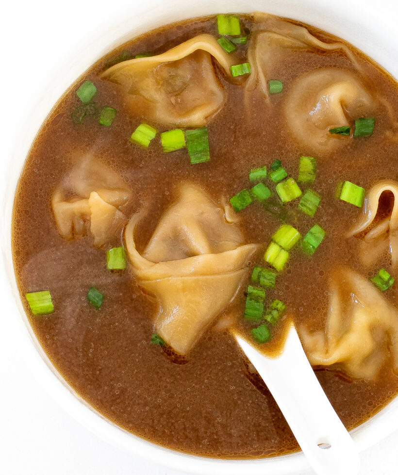 Top down view of white bowl filled with wonton soup.