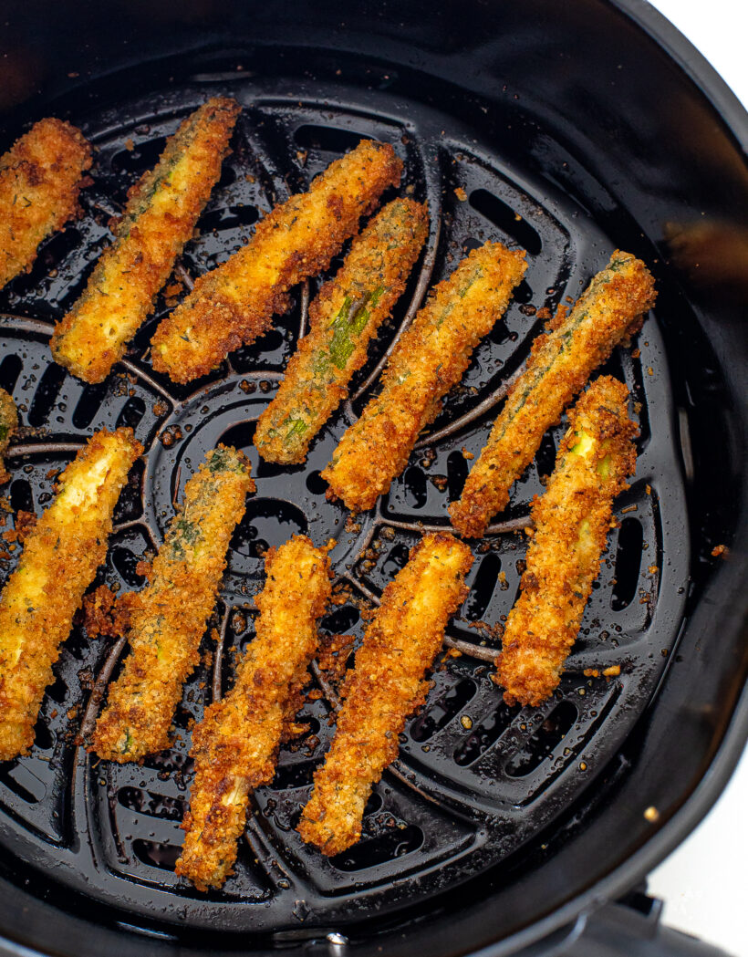 Crispy zucchini fries in an air fryer basket.