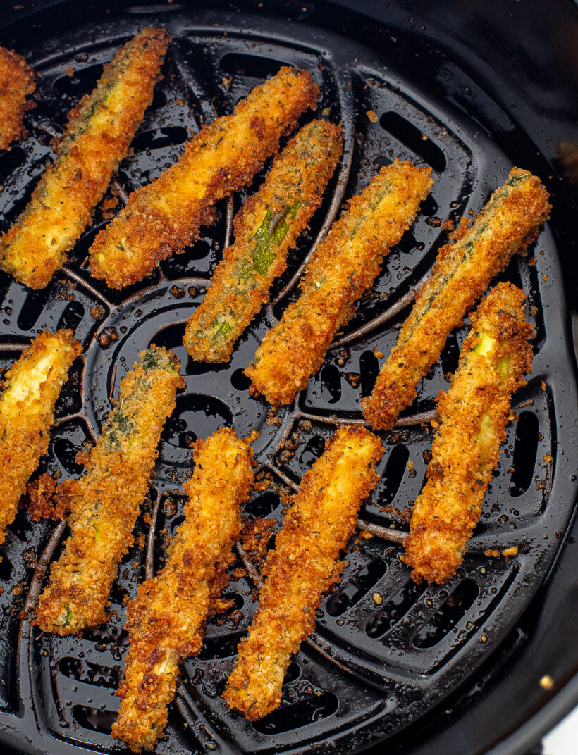 Zucchini fries cooked in the air fryer in the air fryer basket.