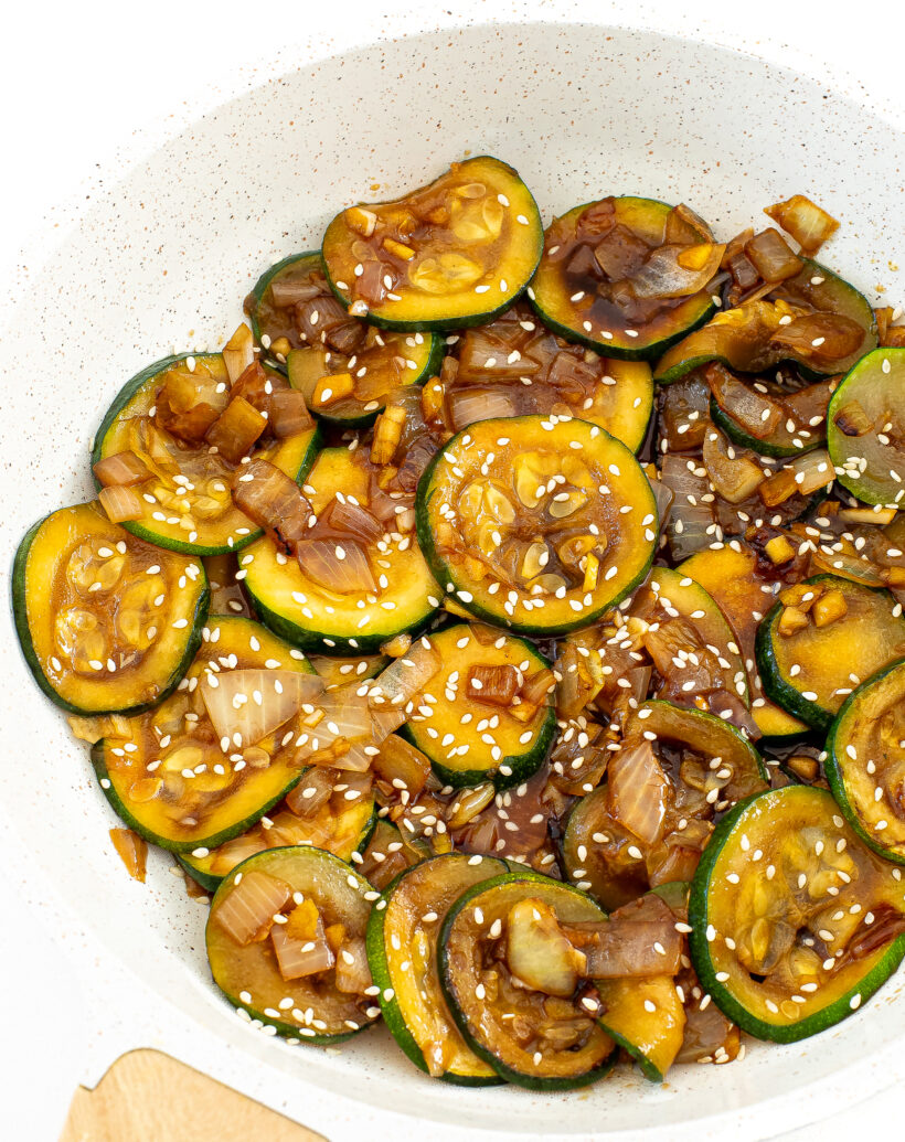 Cooked zucchini stir fry in a white skillet.